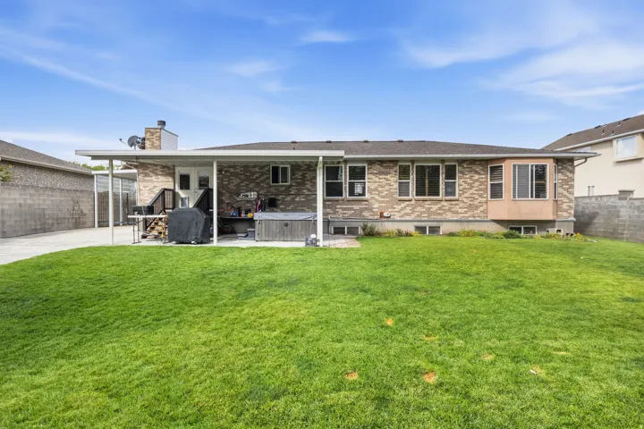 Expansive green lawn with a covered patio, brick exterior, and bay windows