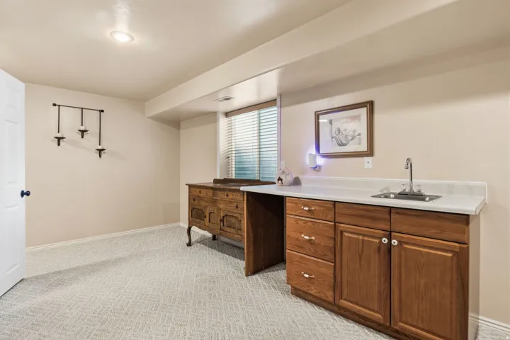 Recessed ceiling lighting, patterned carpeting, built-in cabinetry with a sink, light-toned countertop, and window with blinds