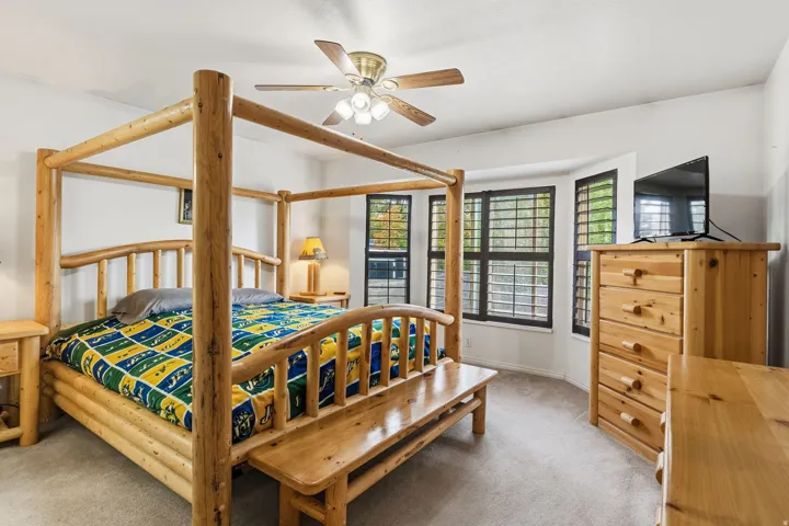 Recessed bay window, plantation shutters, ceiling fan, and carpeted flooring
