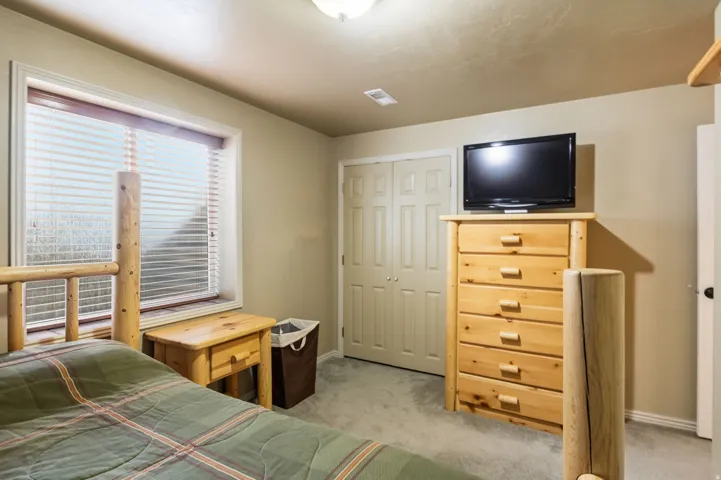 Recessed window with blinds, bi-fold closet doors, and light-colored carpeting