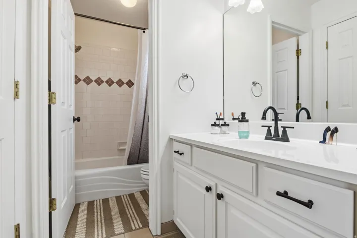 White vanity with black hardware and a solid surface countertop