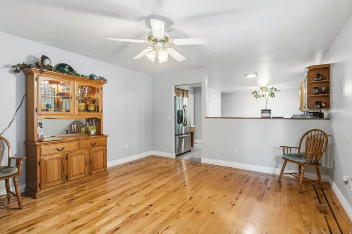 Wood-finish flooring, ceiling fan with integrated lighting, light gray wall tones, recessed lighting, and a partial wall separation