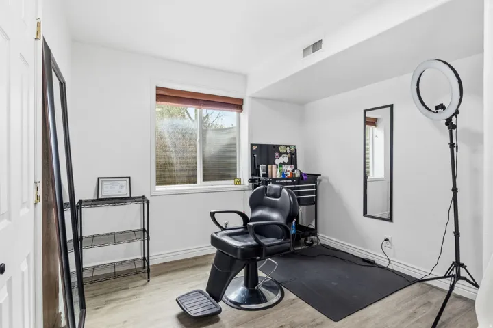 Wood-finish flooring with white walls and a single window featuring a wood-tone blind