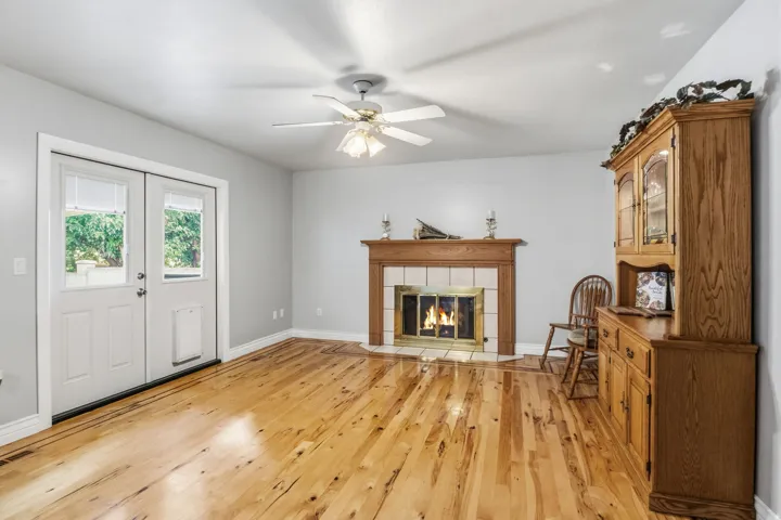 Hardwood flooring throughout, featuring a fireplace with a wood mantel and tile surround