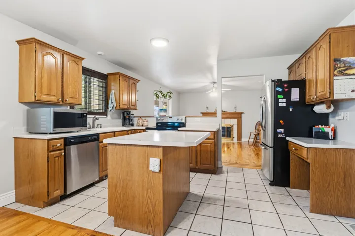 Kitchen featuring wood cabinetry, white countertops, stainless steel appliances, and tile flooring