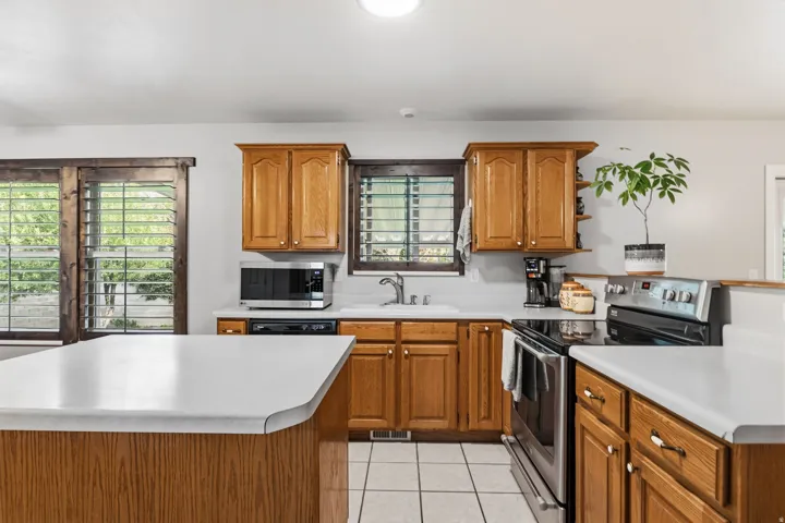 Kitchen featuring wood cabinetry, white countertops, stainless steel appliances, and tile flooring