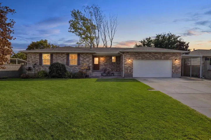 Brick exterior, attached garage, concrete driveway, front lawn, and covered side entry