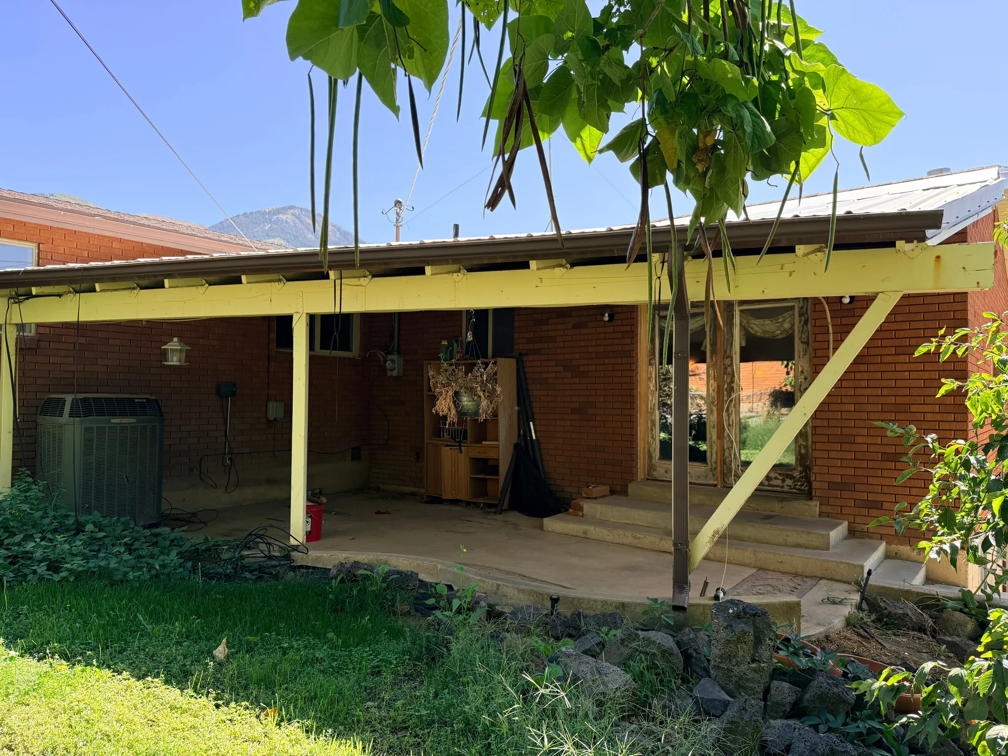 Brick exterior featuring a covered patio with concrete flooring, multiple windows, and exterior lighting