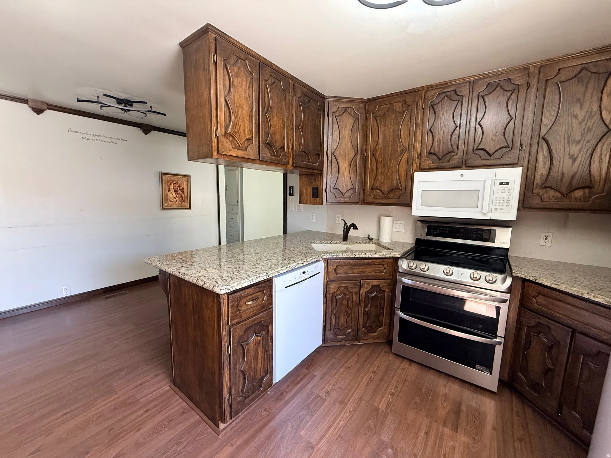 Wood-finish flooring, granite countertops, and wood cabinetry with ornate detailing