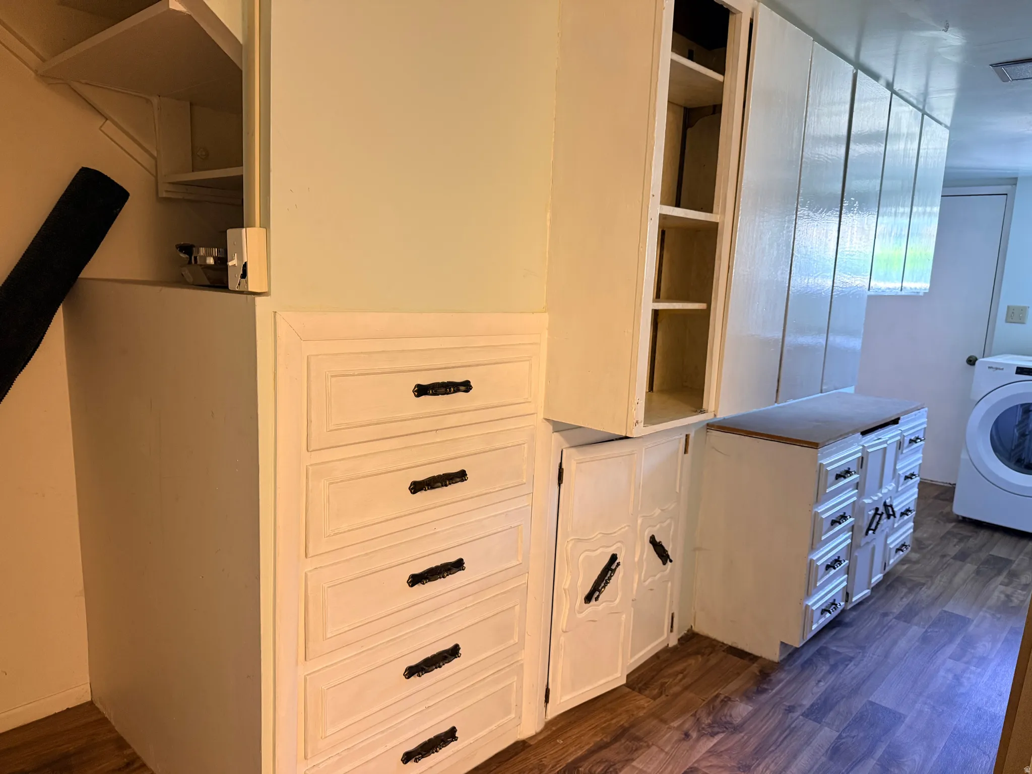 Wood-finish flooring with extensive built-in cabinetry, drawer storage, and wall-mounted shelving