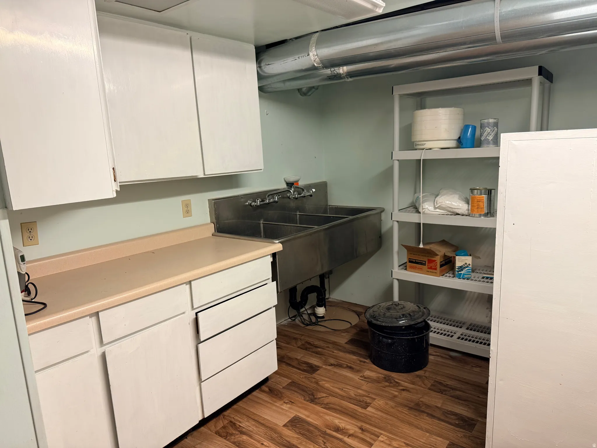 Wood-finish flooring with white cabinetry and a light-toned countertop