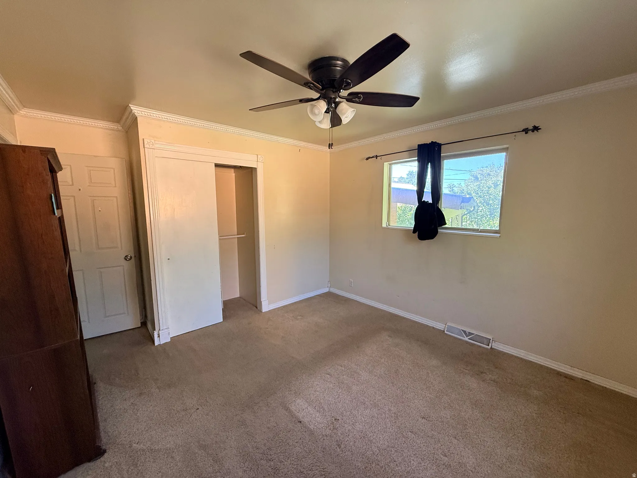 Ceiling fan with integrated lighting, window with hardware, paneled door, and sliding closet doors