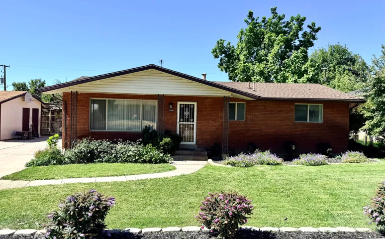 Brick exterior, asphalt shingle roof, concrete pathway, attached storage shed, established landscaping