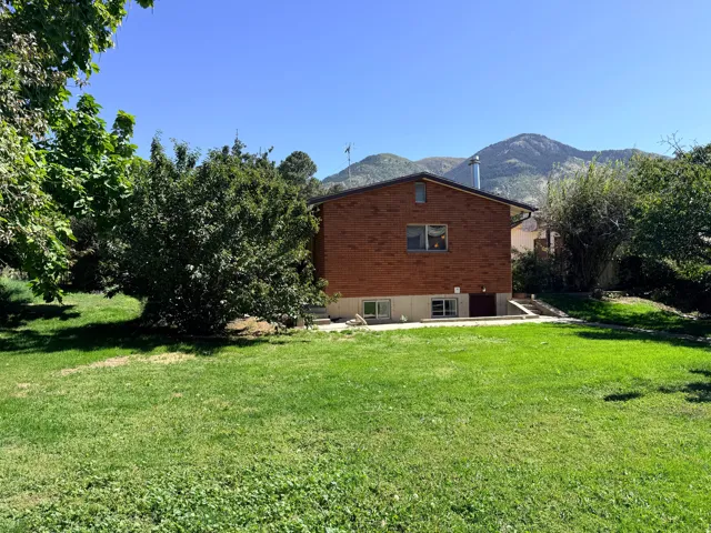Expansive green lawn with mature landscaping and mountain backdrop
