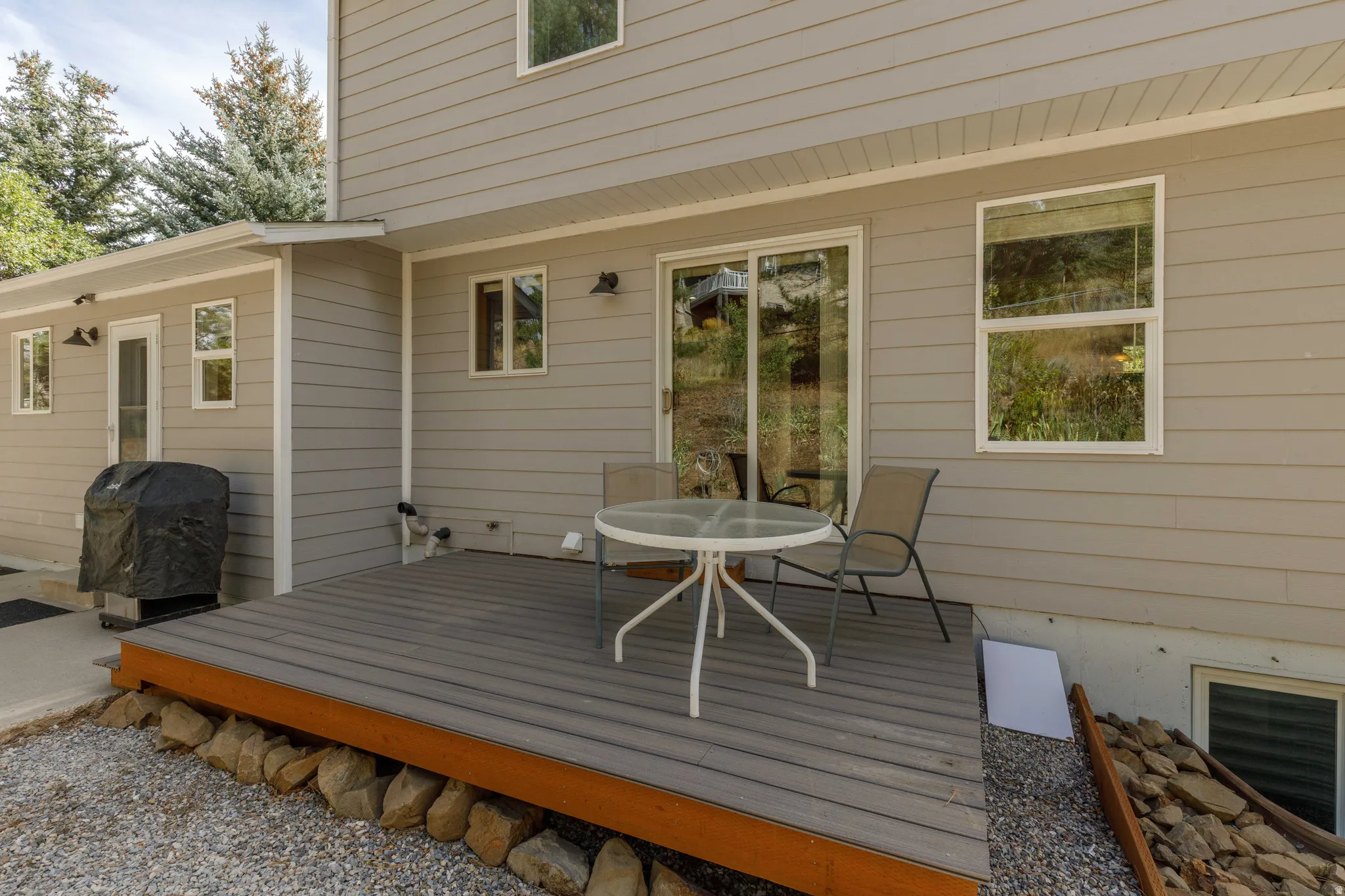 Exterior patio deck with composite decking, light gray siding, and sliding glass door