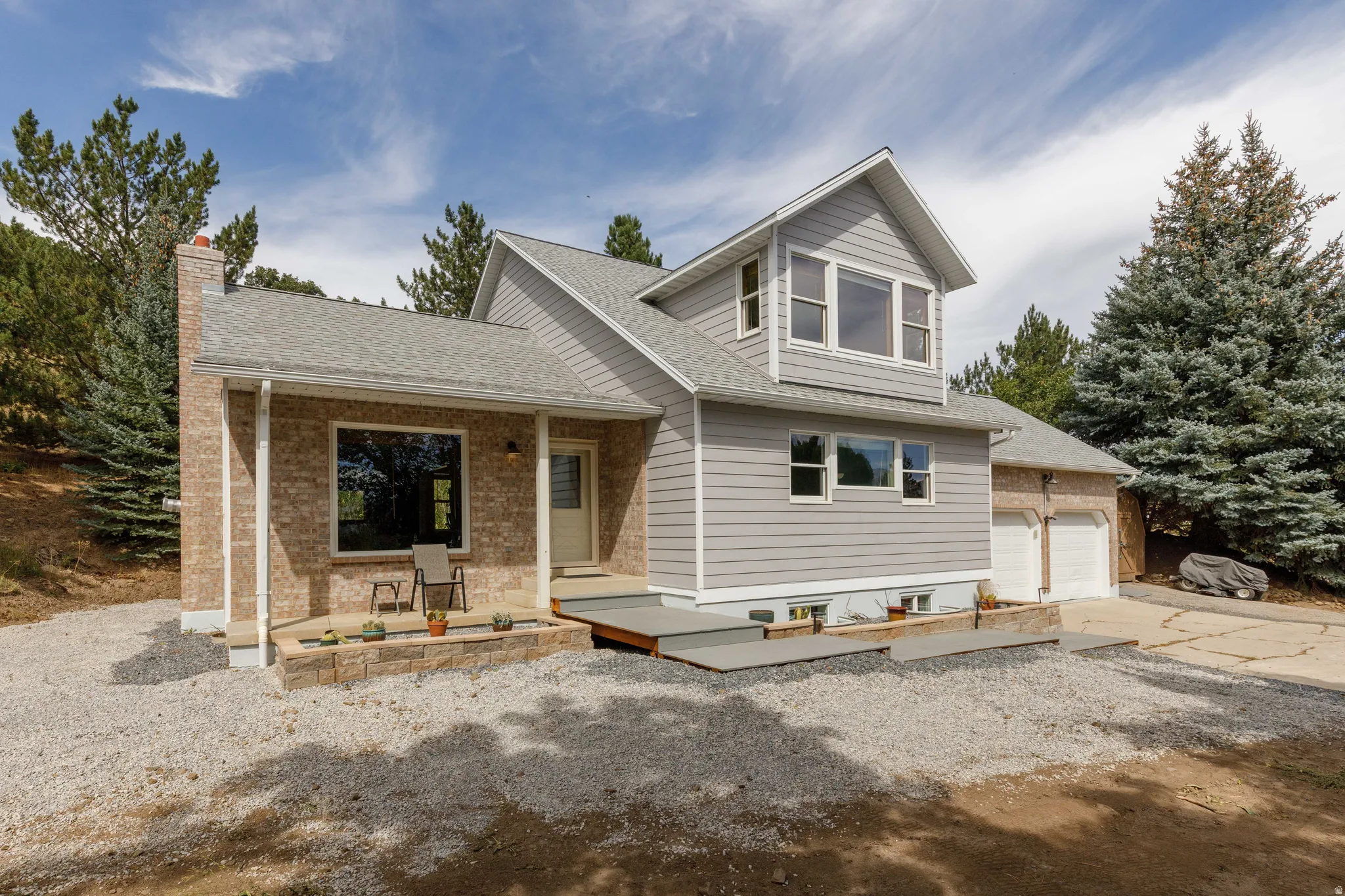 Brick and siding exterior with a multi-level roofline, a front porch, and an attached two-car garage