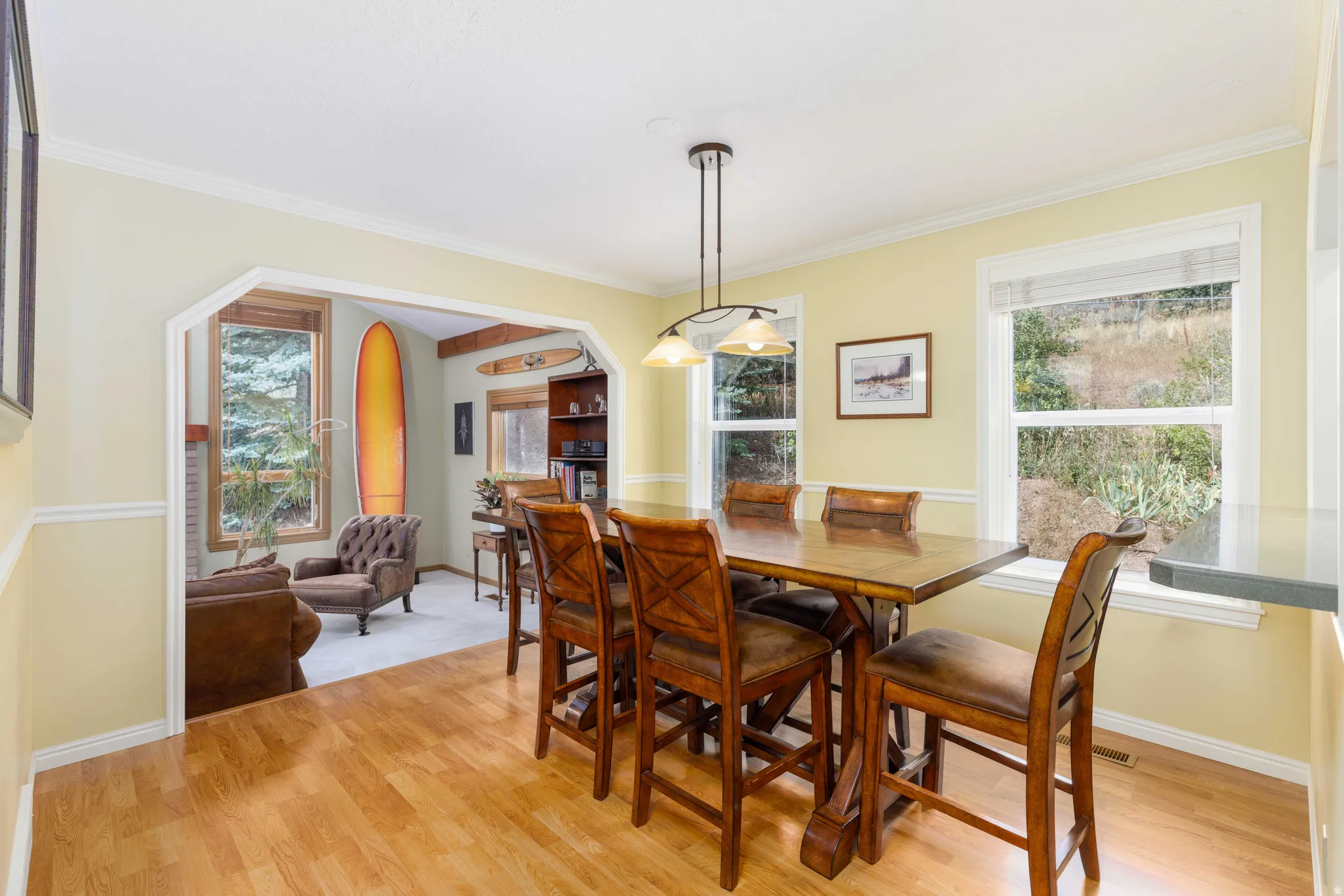 Wood-finish flooring, accent wall trim, and bright windows illuminate this dining area