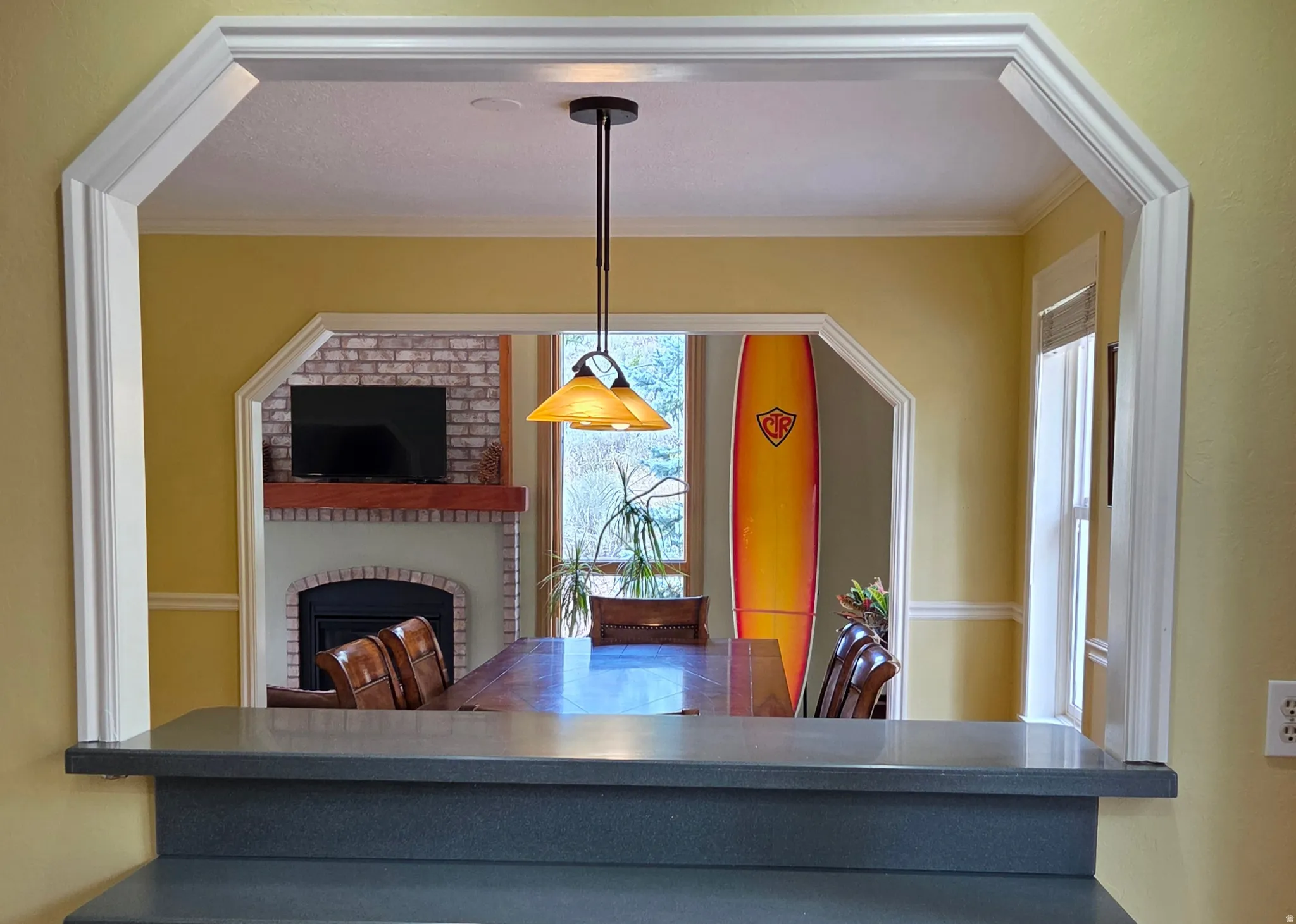 Wide archway opening with substantial trim, dark countertop, and pendant lighting
