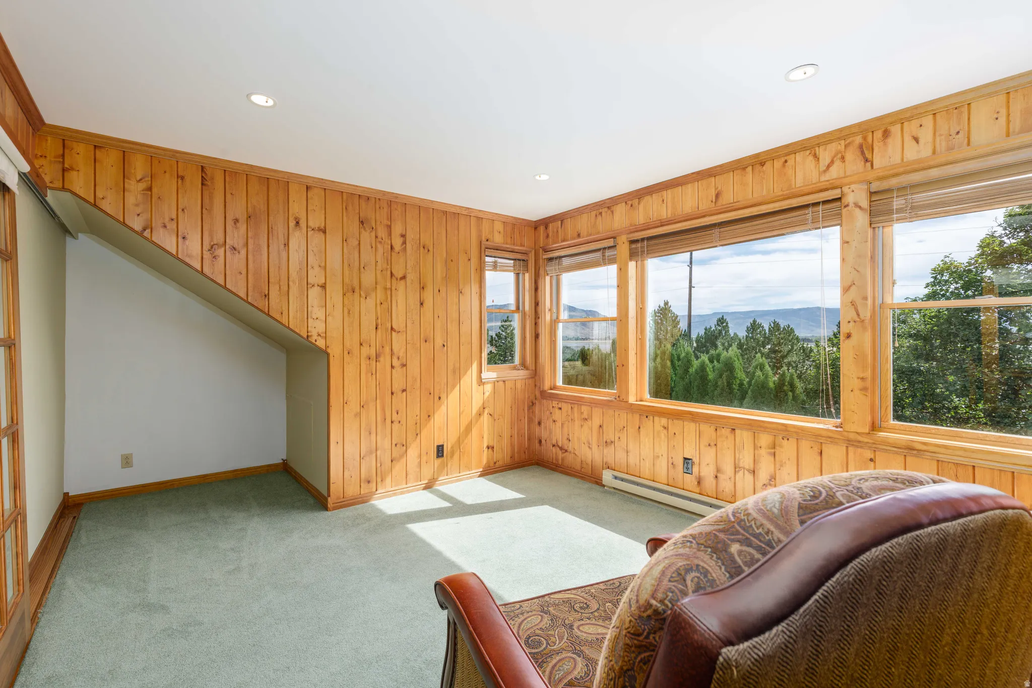 Pine wood paneled walls, recessed lighting, and expansive windows