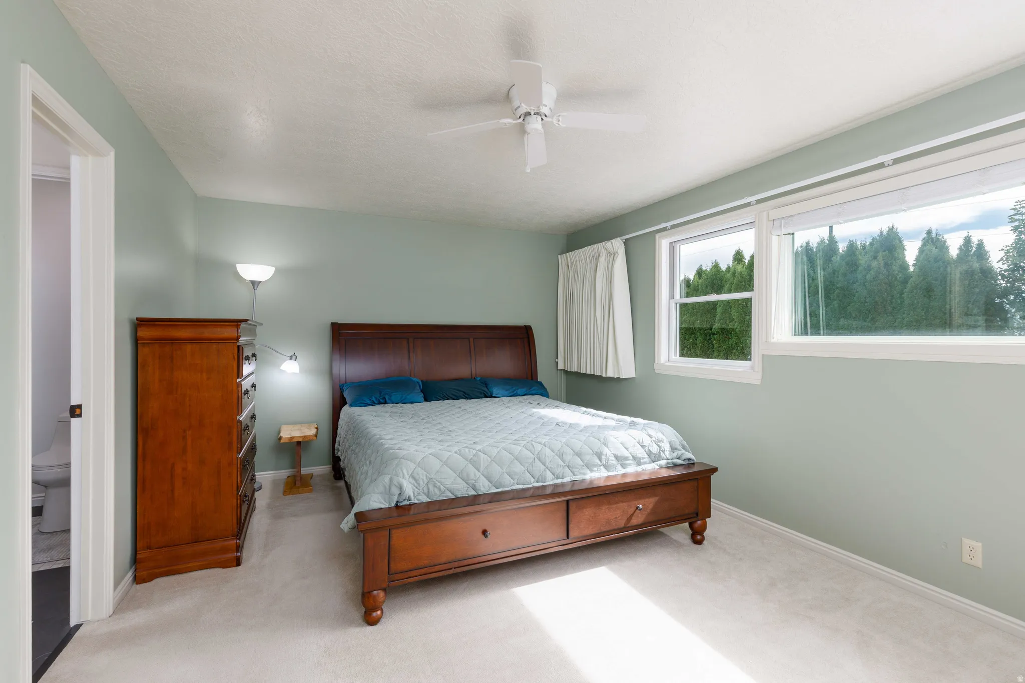 Soft green walls with white trim, a ceiling fan, and carpeted flooring