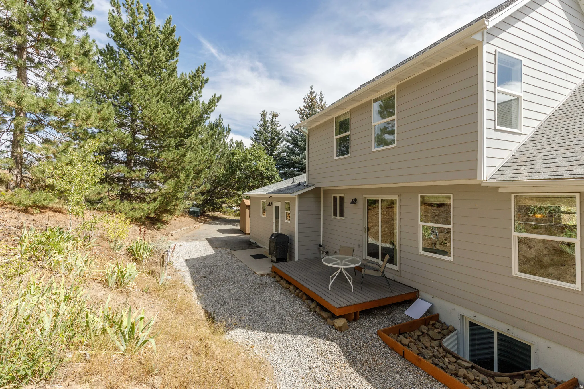 Rear exterior with light gray siding, multi-level design, and a lower-level window well