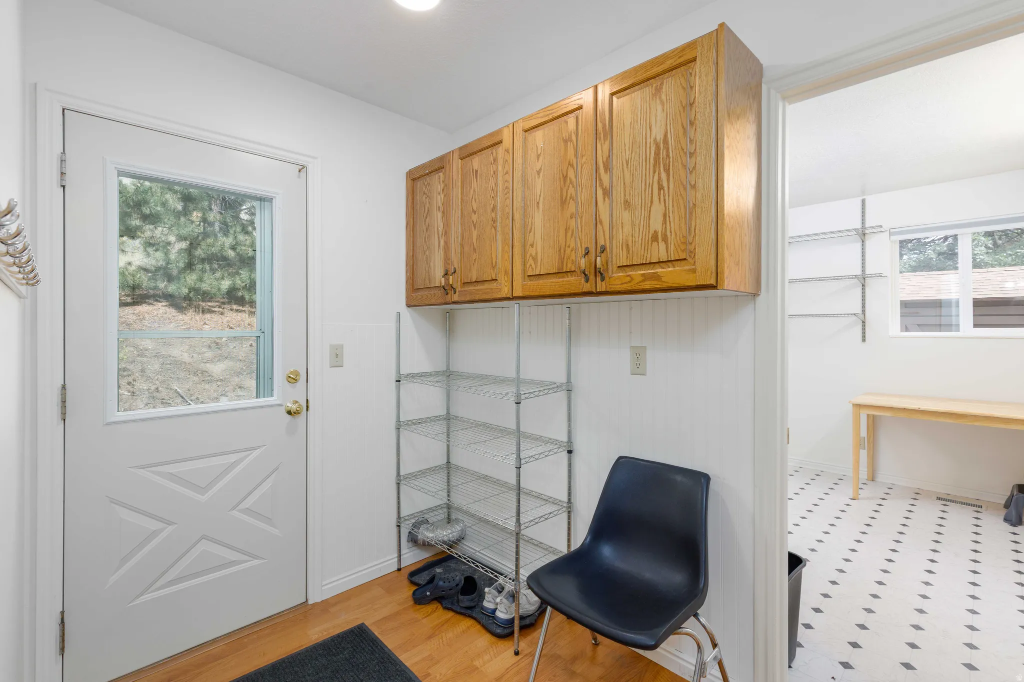 Entryway featuring a white paneled door with window, overhead cabinetry, and wood-finish flooring