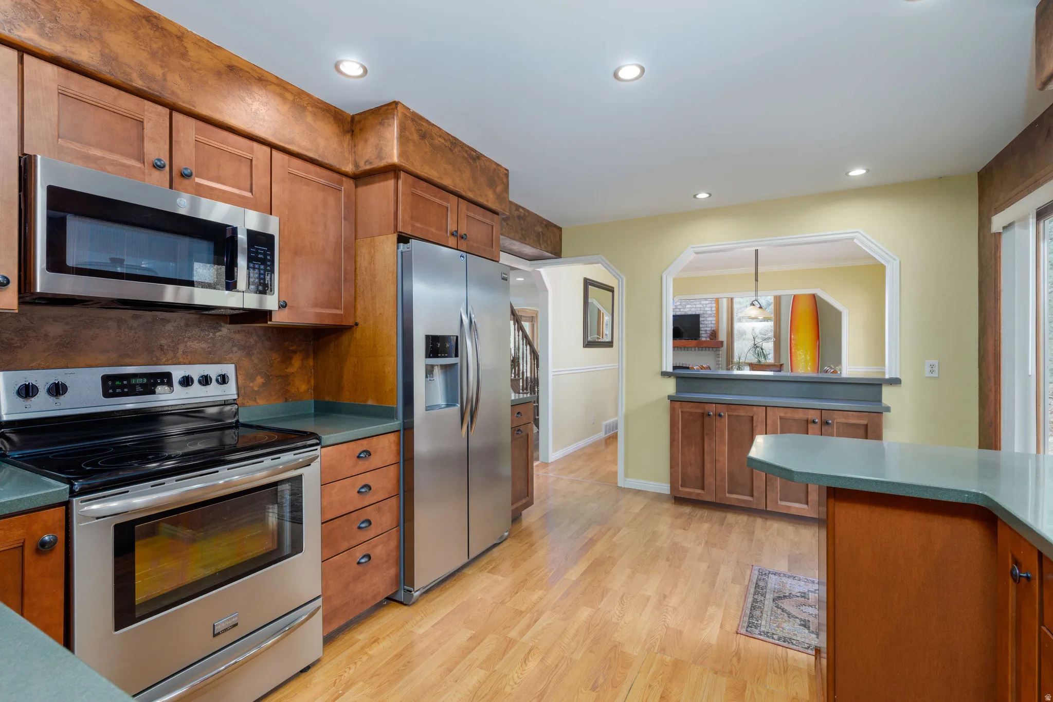 Kitchen featuring stainless steel appliances, wood-finish cabinetry, recessed lighting, and wood-finish flooring