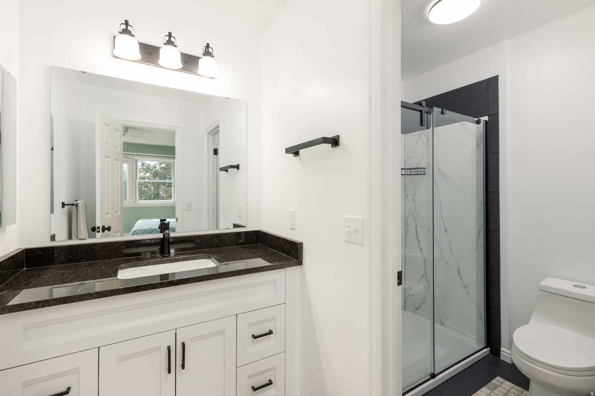 Vanity with a dark stone countertop, undermount sink, and matte black fixtures