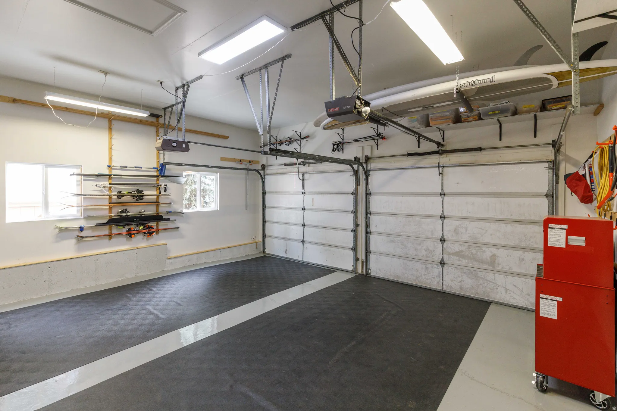 Two overhead garage doors with automatic openers, abundant overhead lighting, and two windows
