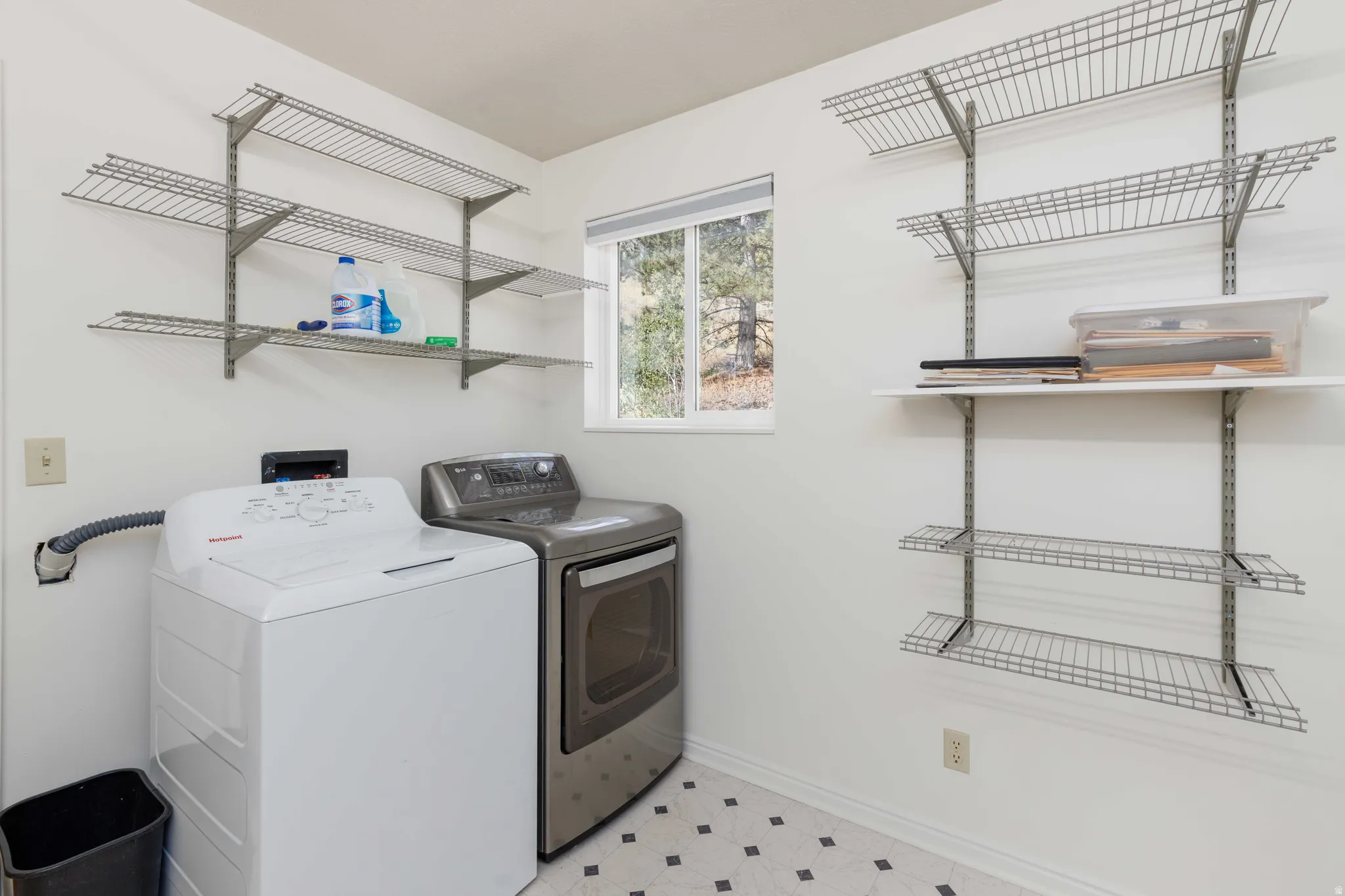 Laundry area with a window, tile flooring, and integrated wall shelving