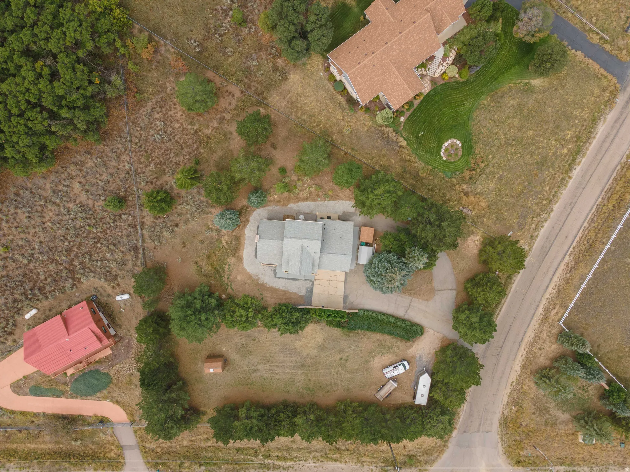 Expansive property featuring multiple structures, mature trees, and natural landscaping