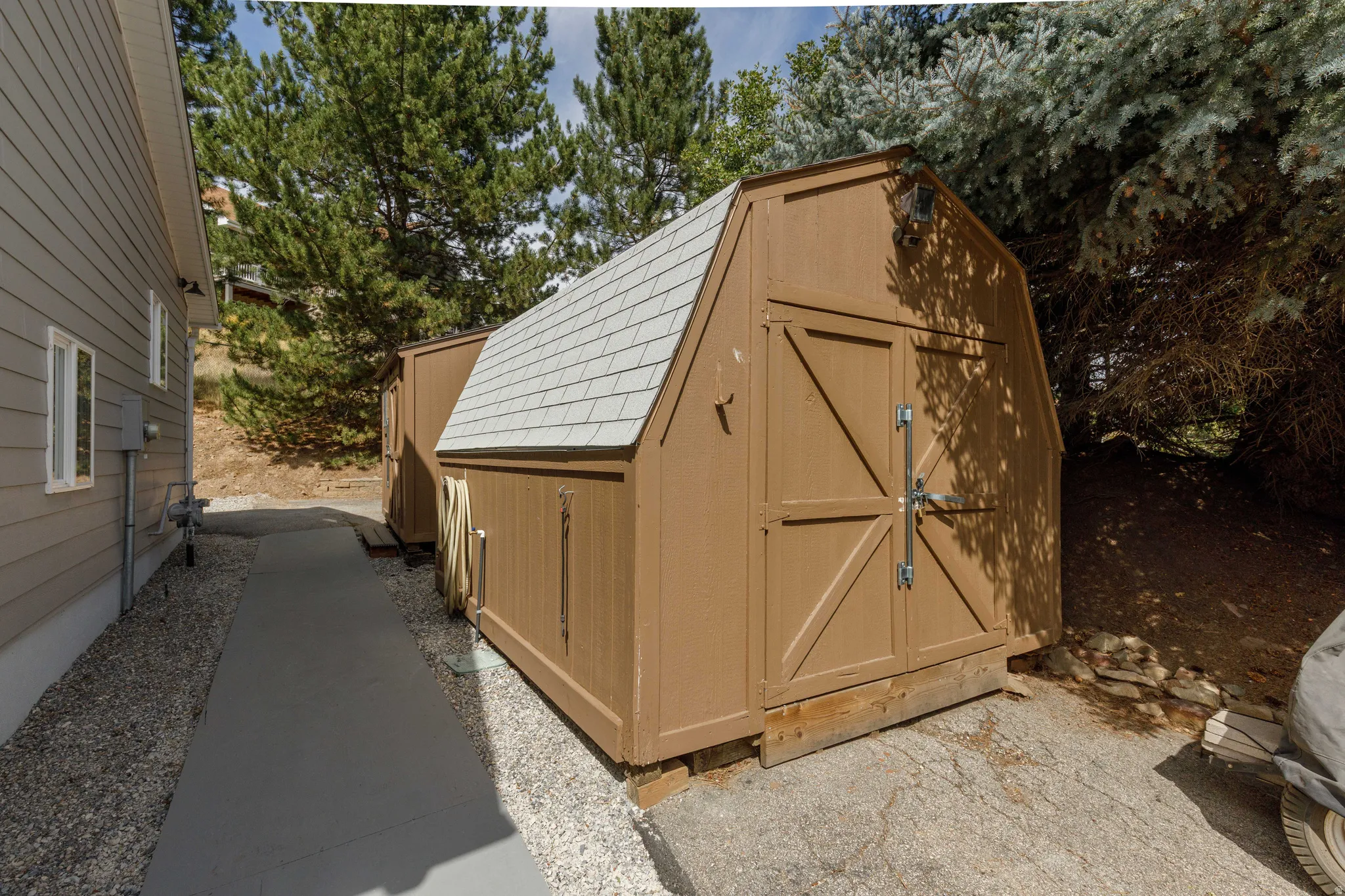 Gable-style shed with double doors, wood siding, and light grey shingle roof