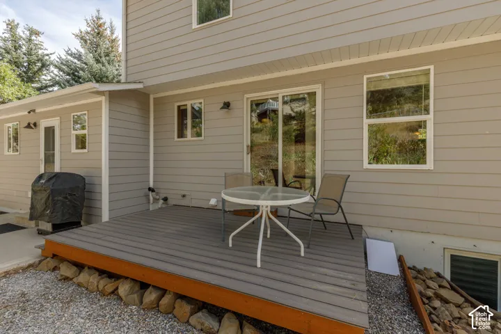 Exterior patio deck with composite decking, light gray siding, and sliding glass door