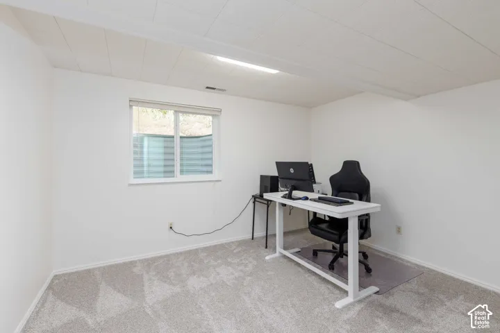 White walls, light-colored carpet, white window trim, and a drop ceiling with integrated lighting