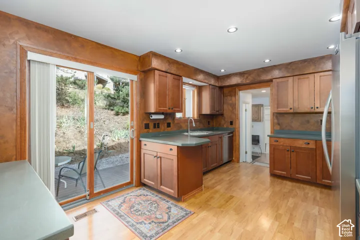 Hardwood-style flooring, recessed lighting, wood cabinetry, stainless steel appliances, and sliding glass doors to outdoor patio