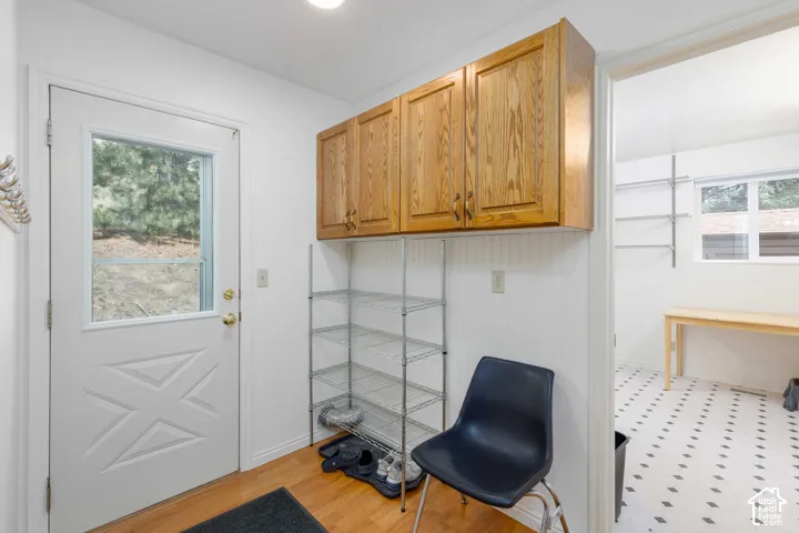 Entryway featuring a white paneled door with window, overhead cabinetry, and wood-finish flooring