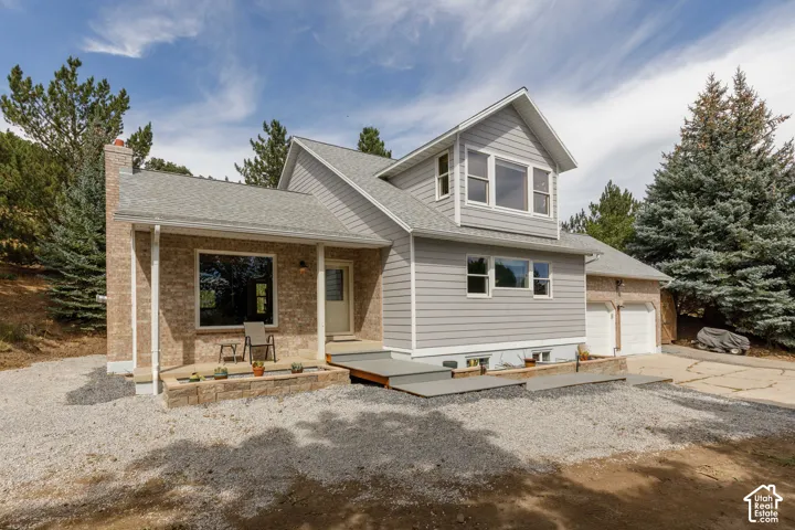 Brick and siding exterior with a multi-level roofline, a front porch, and an attached two-car garage