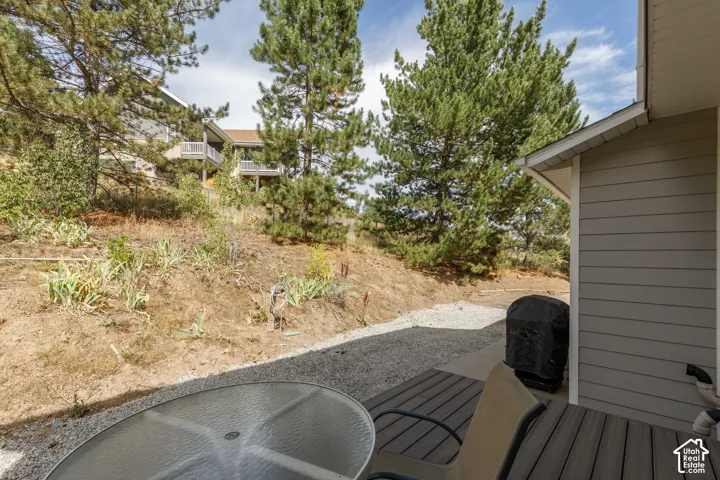 Outdoor deck with wood-finish planks, gravel ground cover, and natural hillside landscaping with mature trees