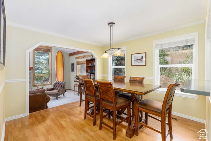 Wood-finish flooring, accent wall trim, and bright windows illuminate this dining area