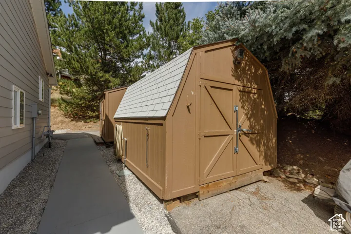 Gable-style shed with double doors, wood siding, and light grey shingle roof