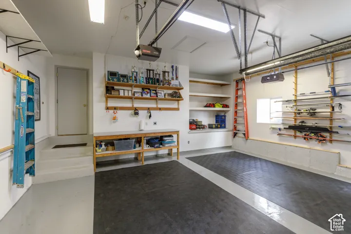 Attached garage featuring a utility sink, built-in shelving, durable flooring, and fluorescent overhead lighting