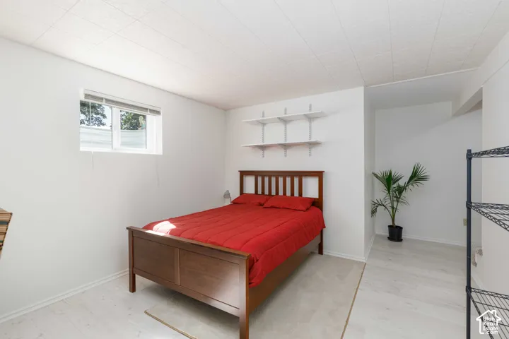 White walls with light wood-finish flooring, a window offering natural light, and built-in shelving