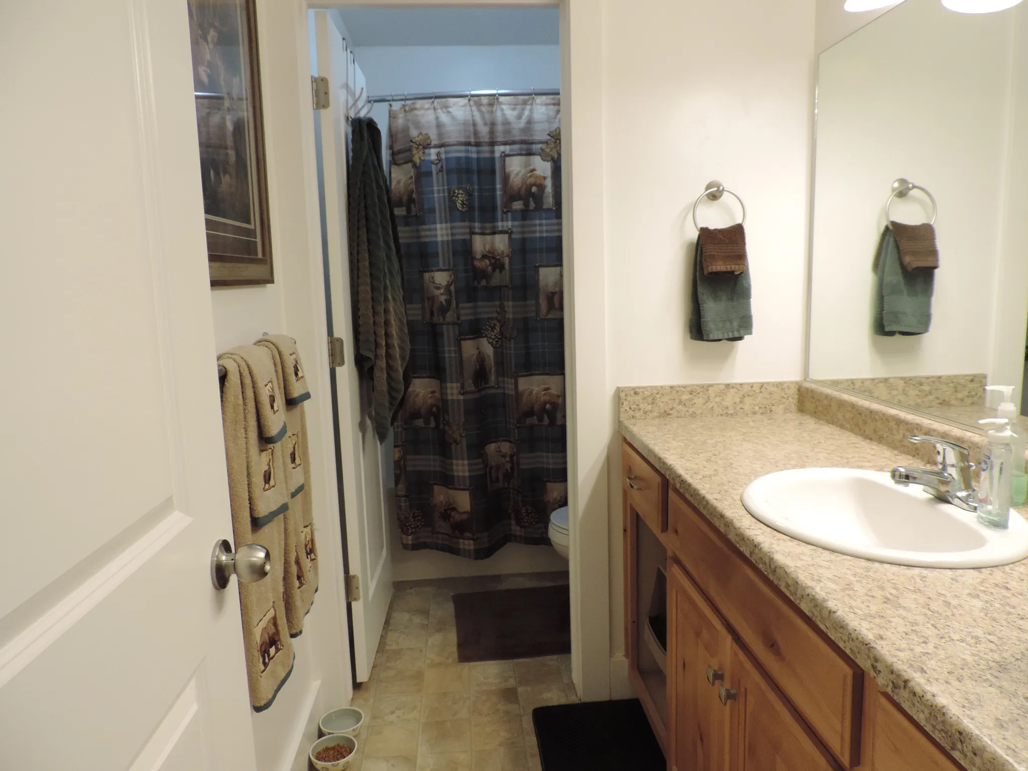 Bathroom featuring a vanity with wood cabinetry, an integrated sink, and a speckled countertop