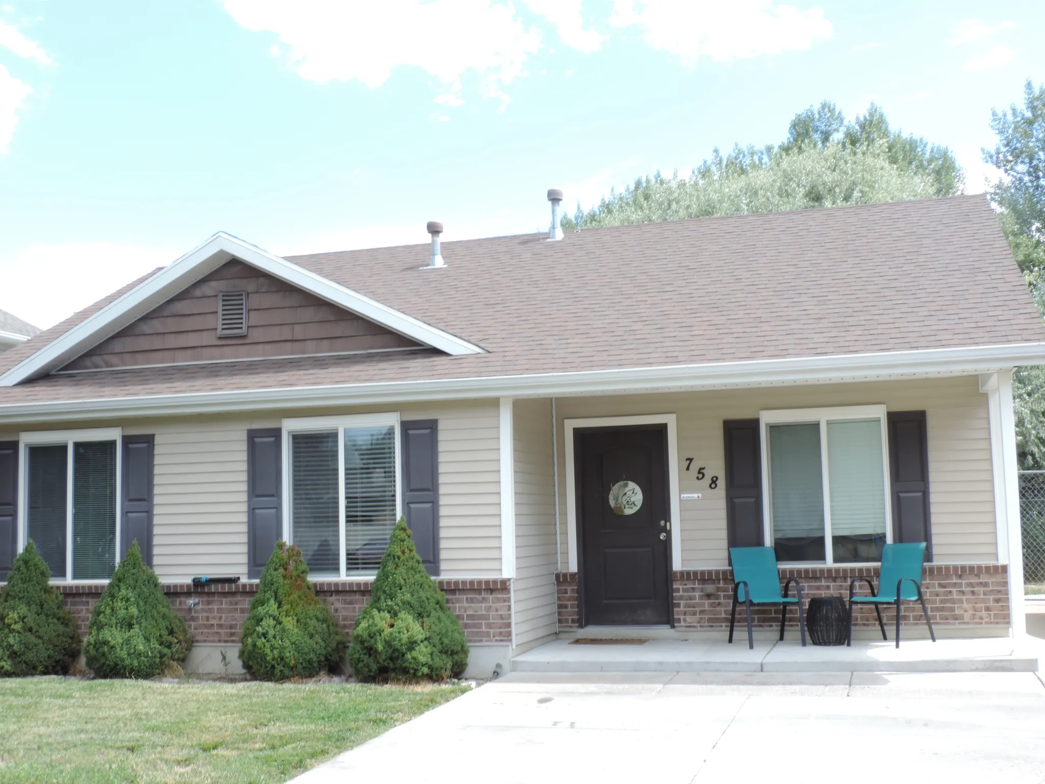 Siding and brick facade with a brown shingle roof