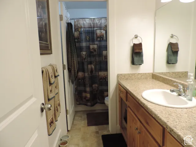 Bathroom featuring a vanity with wood cabinetry, an integrated sink, and a speckled countertop