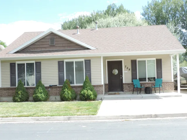 Siding exterior with a brick foundation, dark shutters, and a covered entry