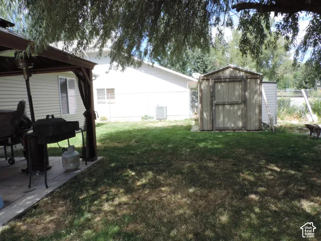 Spacious backyard with a shaded patio, permanent storage shed, and mature trees