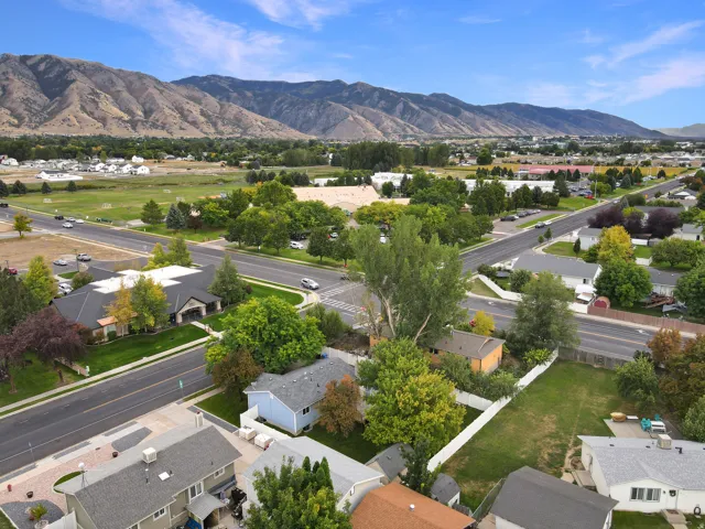 Mountain backdrop, residential street, green spaces, scattered mature trees, clear blue sky
