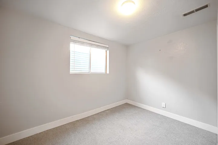 Recessed window with blinds, light-toned walls, and neutral carpeting