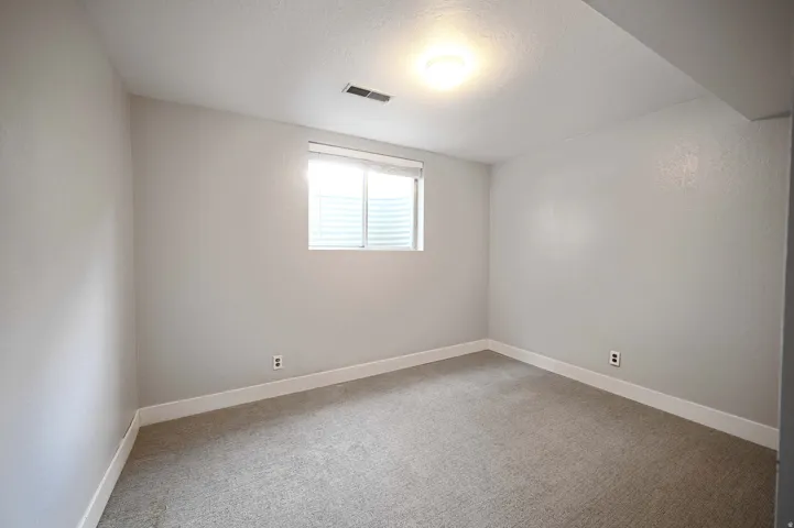 Recessed window with white blinds, neutral carpeting, and overhead lighting